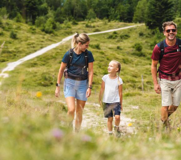 Glückliche Familie wandert entlang einer Bergwiese