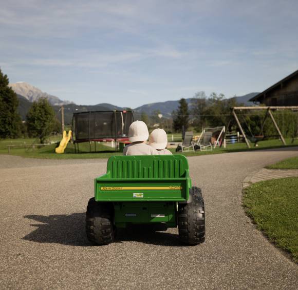 Kinder fahren im Spielzeugauto entlang eines Wegs
