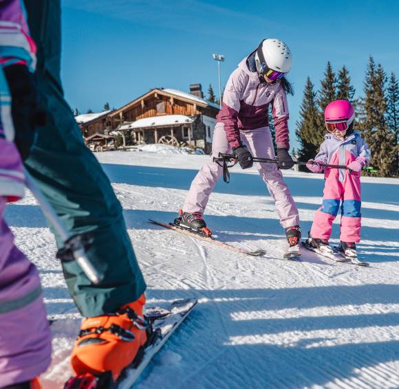 Mutter zeigt Kind wie es mit den Skier umgeht