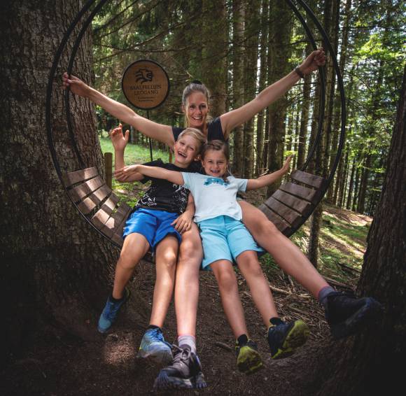 Mutter mit Ihren Kindern sitzen auf einer runden Bank im Wald