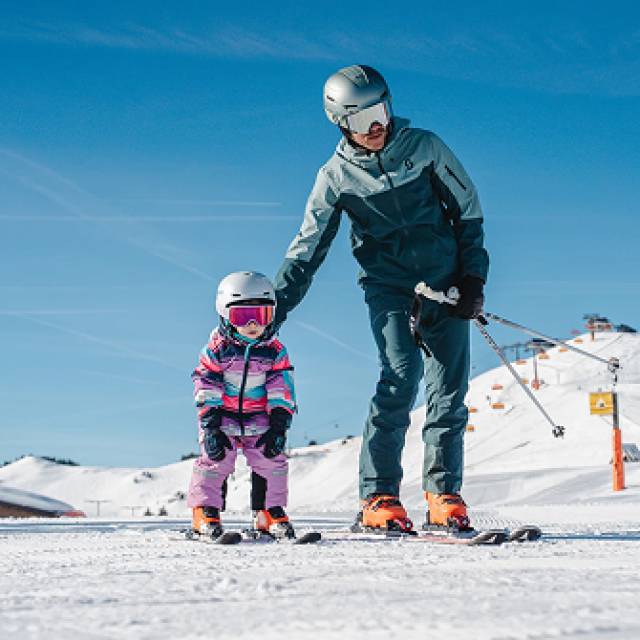 Vater und Kind beim Skifahren auf der Piste in Leogang